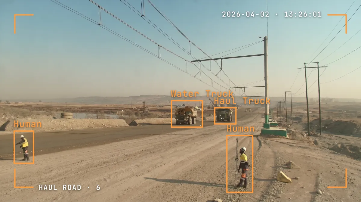 Haul road camera view with trucks and workers detected beneath the overhead trolley line.